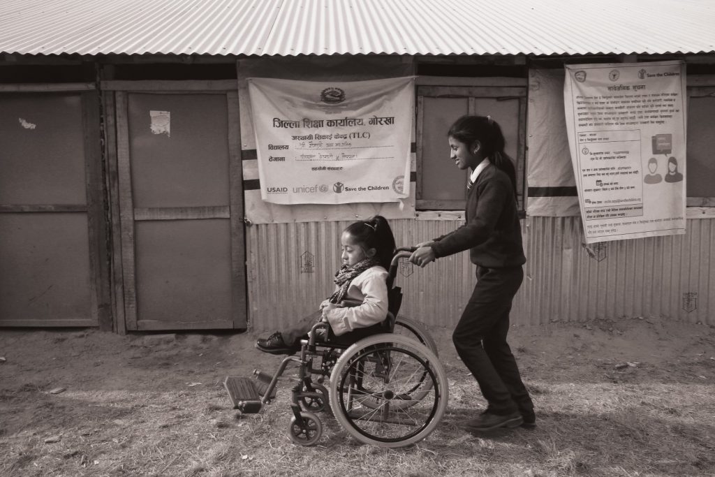 a student in a wheelchair is being helped by her friend in her school