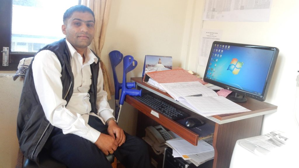 a person at his workdesk. His workdesk contains a computer and other papers