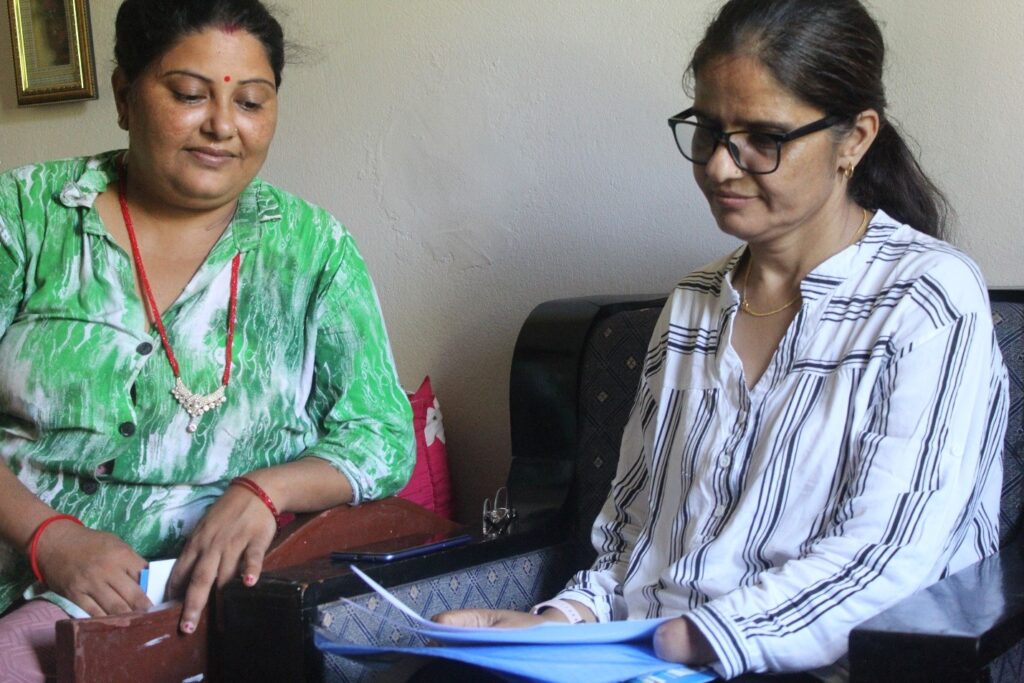Two lady are seating together and one is showing the document.